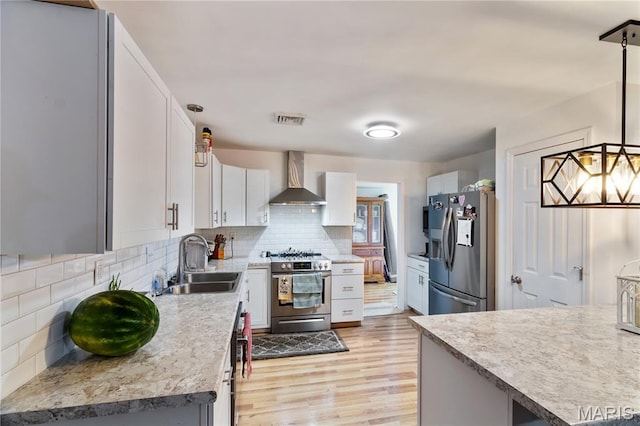 407 N 11th St, De Soto, MO 63020 - kitchen with stainless steel appliances, wall chimney exhaust hood, light wood-type flooring, backsplash, and light countertops