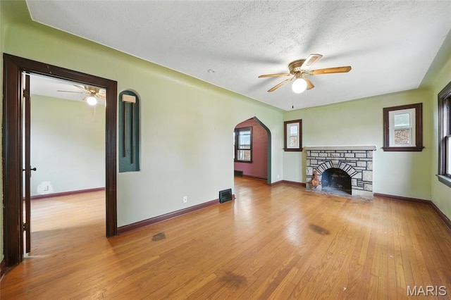 8609 Engler Ave, Saint Louis, MO 63114 - unfurnished living room with ceiling fan, wood-type flooring, arched walkways, a textured ceiling, and a fireplace