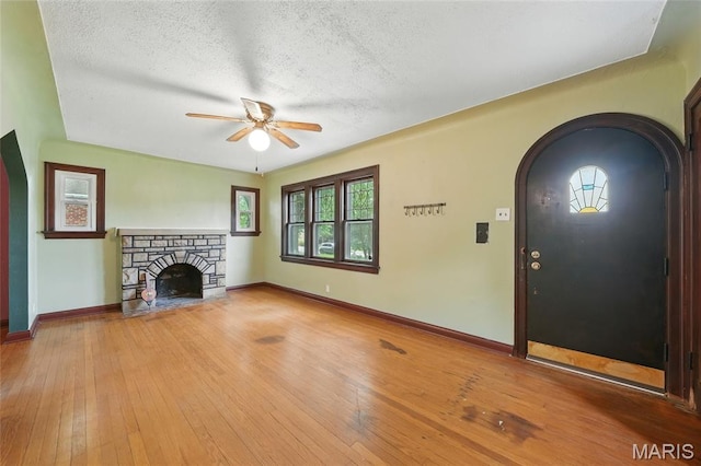 8609 Engler Ave, Saint Louis, MO 63114 - unfurnished living room featuring arched walkways, a ceiling fan, a textured ceiling, hardwood / wood-style flooring, and a fireplace