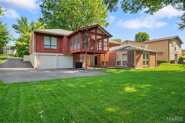 11894 Featherwood Dr, Creve Coeur Township, MO 63146 - rear view of house with a garage, asphalt driveway, brick siding, a sunroom, and a lawn