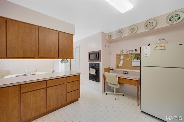 6235 Meadowlark Ln, Troy, MO 63379 - kitchen with black appliances, light countertops, light flooring, a desk, and brown cabinetry