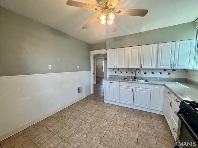 6328 Bradley Ave, Saint Louis, MO 63139 - kitchen with gas stove, light countertops, ceiling fan, white cabinetry, and a wainscoted wall