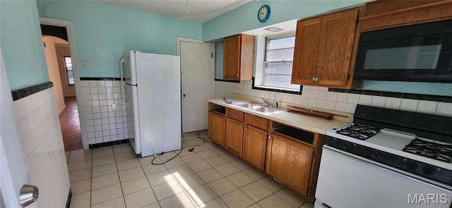5464 Lindenwood Ave, Saint Louis, MO 63109 - kitchen featuring white appliances, brown cabinets, plenty of natural light, tile walls, and a wainscoted wall