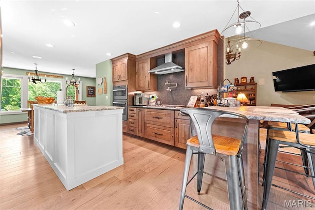 727 Madison Vly, Wildwood, MO 63005 - kitchen with a chandelier, wall chimney range hood, stainless steel double oven, light wood-style flooring, and recessed lighting