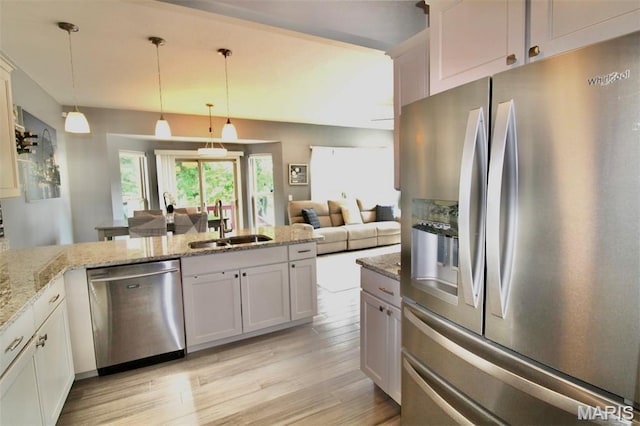 1001 Windsor Crest Ct, Cottleville, MO 63376 - kitchen with stainless steel appliances, light wood-style floors, light stone counters, pendant lighting, and a peninsula
