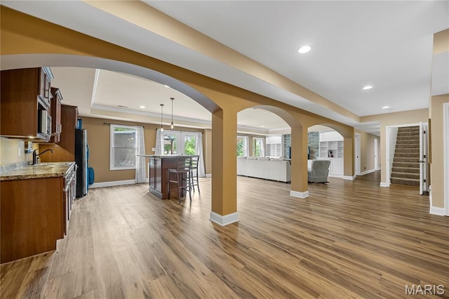 105 Cypress Meadows Dr, Wentzville, MO 63385 - unfurnished living room with arched walkways, wood finished floors, a tray ceiling, stairs, and recessed lighting
