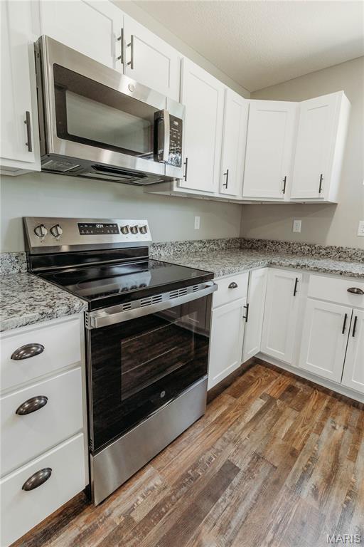 501 W 2nd, Dixon, MO 65459 - kitchen with appliances with stainless steel finishes, light wood-style floors, white cabinetry, and light stone countertops