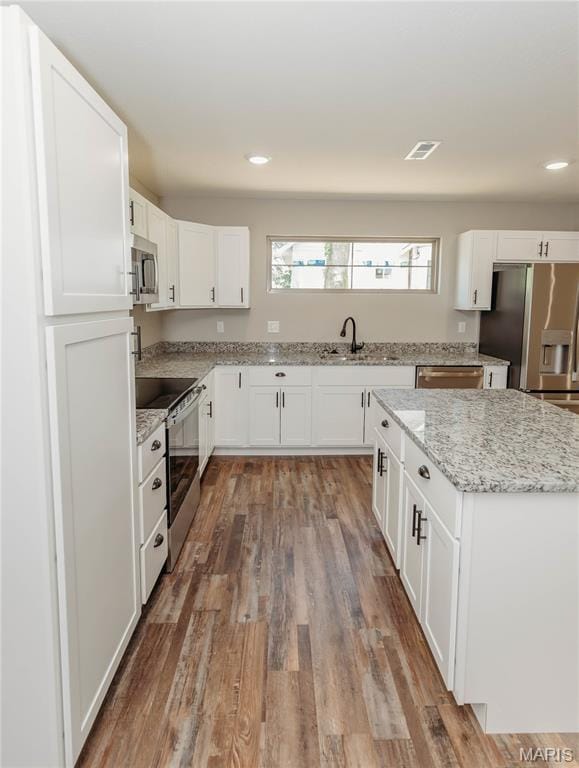 501 W 2nd, Dixon, MO 65459 - kitchen with stainless steel appliances, wood finished floors, white cabinetry, recessed lighting, and light stone countertops