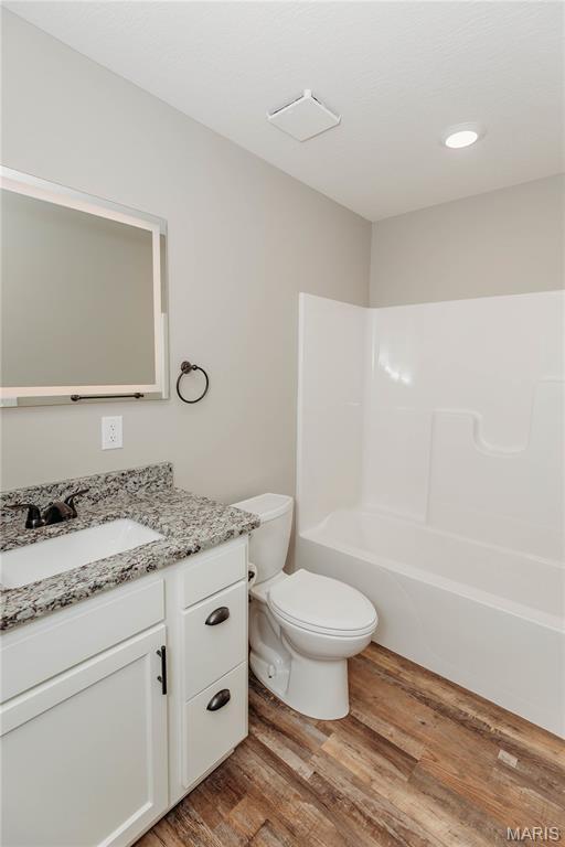 501 W 2nd, Dixon, MO 65459 - bathroom featuring vanity, wood finished floors, and washtub / shower combination