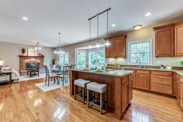 1515 Dietrich Glen Dr, Ballwin, MO 63021 - kitchen with a breakfast bar area, light wood-type flooring, ceiling fan, a center island, and decorative backsplash