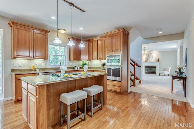 1515 Dietrich Glen Dr, Ballwin, MO 63021 - kitchen with double oven, a kitchen breakfast bar, a center island, a glass covered fireplace, and ceiling fan