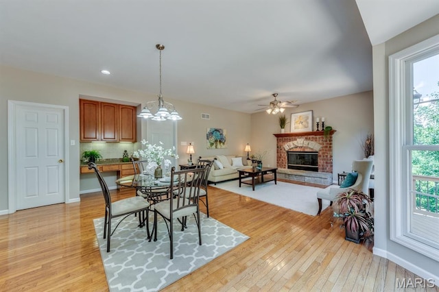 1515 Dietrich Glen Dr, Ballwin, MO 63021 - dining area with a brick fireplace, light wood-type flooring, a ceiling fan, a chandelier, and recessed lighting