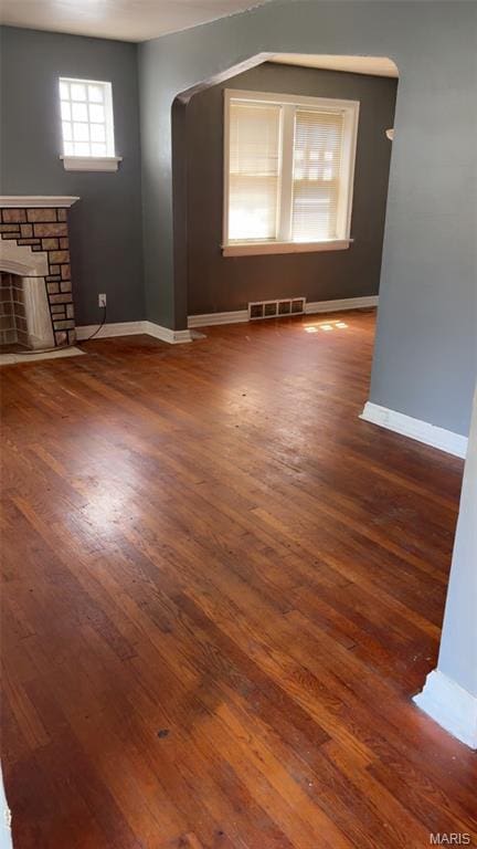 1178 Riverview Blvd, Saint Louis, MO 63147 - unfurnished living room with arched walkways, wood finished floors, and a stone fireplace