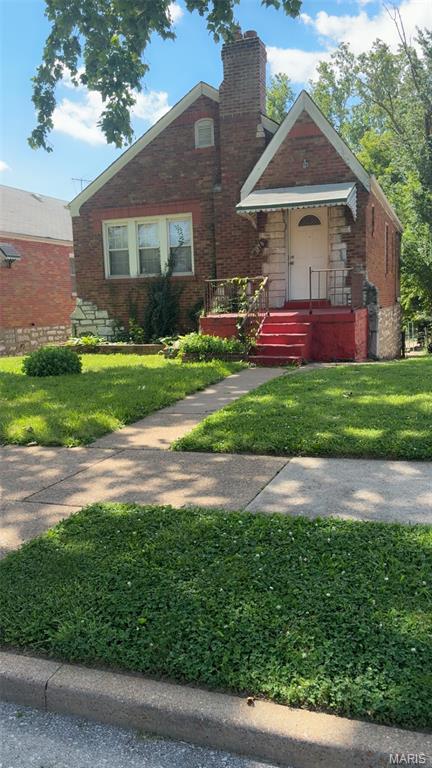 1178 Riverview Blvd, Saint Louis, MO 63147 - view of front facade with a chimney, a front yard, and brick siding
