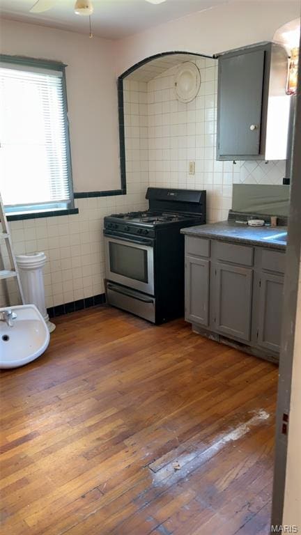 1178 Riverview Blvd, Saint Louis, MO 63147 - kitchen featuring stainless steel gas range oven, tile walls, gray cabinets, dark wood-type flooring, and dark countertops