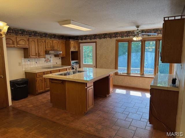 7 Forest Hills Dr, Washington, MO 63090 - kitchen featuring a ceiling fan, a center island with sink, decorative backsplash, healthy amount of natural light, and a textured ceiling