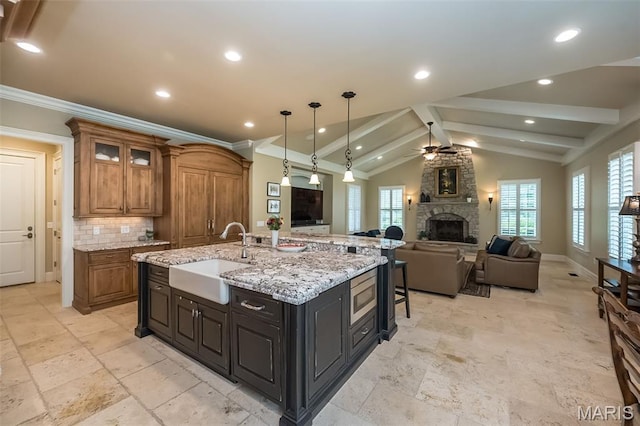 21 Lynnbrook Rd, Saint Louis, MO 63131 - kitchen featuring a stone fireplace, a ceiling fan, open floor plan, brown cabinets, and stainless steel microwave