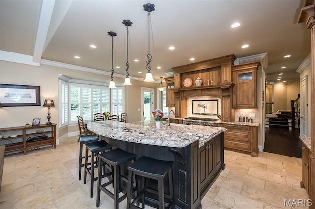 21 Lynnbrook Rd, Saint Louis, MO 63131 - kitchen with stone tile floors, brown cabinets, crown molding, backsplash, and a spacious island