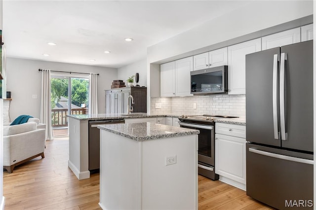 1905 King Arthur Ct, Maryland Heights Township, MO 63146 - kitchen featuring stainless steel appliances, a peninsula, white cabinetry, decorative backsplash, and light wood-type flooring