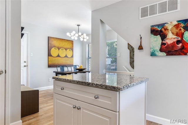 1905 King Arthur Ct, Maryland Heights Township, MO 63146 - kitchen with light wood-style floors, light stone counters, a chandelier, white cabinets, and a kitchen island