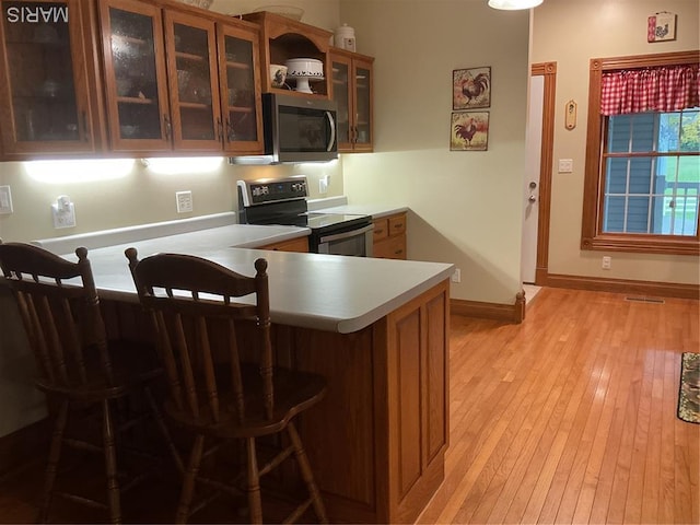 11996 County Road 3290, Rolla, MO 65401 - kitchen with appliances with stainless steel finishes, light countertops, a peninsula, light wood finished floors, and glass insert cabinets