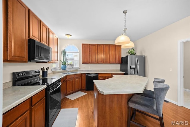 6817 Dunhill Dr, Fairview Heights, IL 62208 - kitchen with black appliances, light wood finished floors, a kitchen breakfast bar, light countertops, and a kitchen island