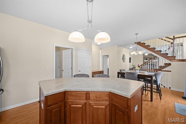 6817 Dunhill Dr, Fairview Heights, IL 62208 - kitchen with light wood-type flooring, a kitchen island, a chandelier, and light countertops