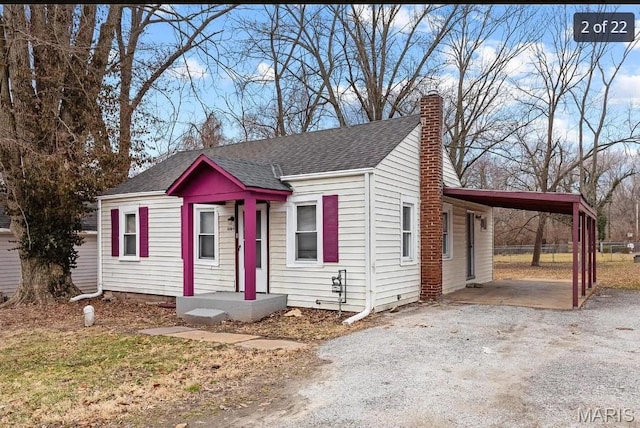 10109 Imperial Dr, Saint Louis, MO 63136 - view of front facade featuring roof with shingles, a chimney, dirt driveway, and an attached carport