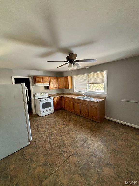10109 Imperial Dr, Saint Louis, MO 63136 - kitchen with white appliances, under cabinet range hood, brown cabinets, ceiling fan, and light countertops