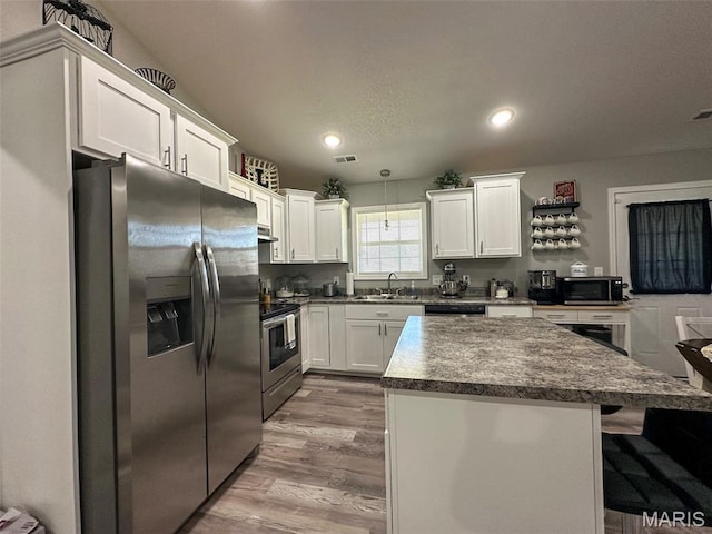326 Apple Park Way, Poplar Bluff, MO 63901 - kitchen with appliances with stainless steel finishes, wood finished floors, white cabinetry, a breakfast bar area, and recessed lighting