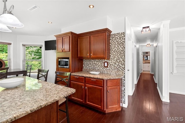 351 N 66th St, Belleville, IL 62223 - kitchen with stainless steel microwave, light stone counters, tasteful backsplash, a breakfast bar area, and dark wood-style flooring