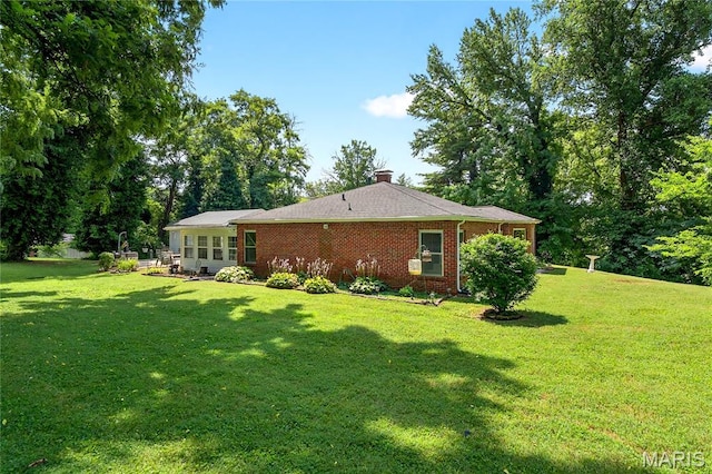 351 N 66th St, Belleville, IL 62223 - rear view of house featuring a lawn, brick siding, and a chimney