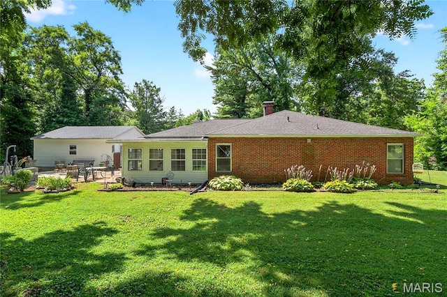 351 N 66th St, Belleville, IL 62223 - rear view of house featuring a patio, a lawn, a chimney, and brick siding