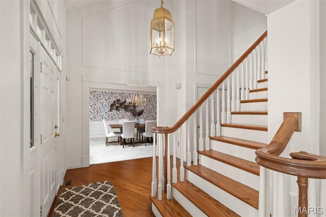 649 Westledge Ct, Des Peres, MO 63131 - entryway with a chandelier, stairs, dark wood-style floors, and a decorative wall