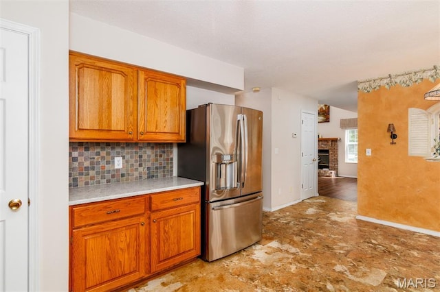 170 Coventry Way, Highland, IL 62249 - kitchen with stainless steel fridge with ice dispenser, decorative backsplash, brown cabinets, light countertops, and a fireplace