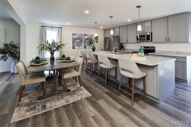 3092 Pirogue St, Saint Charles, MO 63301 - kitchen with stainless steel appliances, gray cabinetry, a kitchen breakfast bar, recessed lighting, and dark wood finished floors