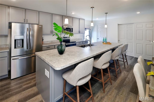 3092 Pirogue St, Saint Charles, MO 63301 - kitchen with stainless steel appliances, gray cabinetry, dark wood-style flooring, a kitchen bar, and recessed lighting