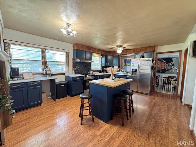 56319 Meyer Trl, Hannibal, MO 63401 - kitchen with stainless steel appliances, blue cabinetry, a breakfast bar area, and light wood-style floors