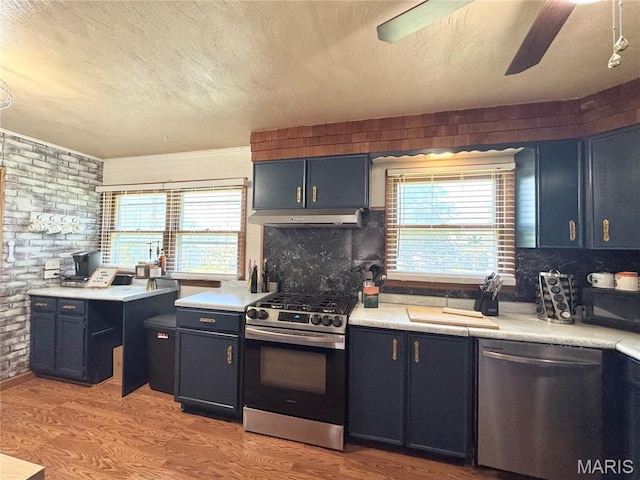 56319 Meyer Trl, Hannibal, MO 63401 - kitchen with appliances with stainless steel finishes, under cabinet range hood, a textured ceiling, brick wall, and light countertops