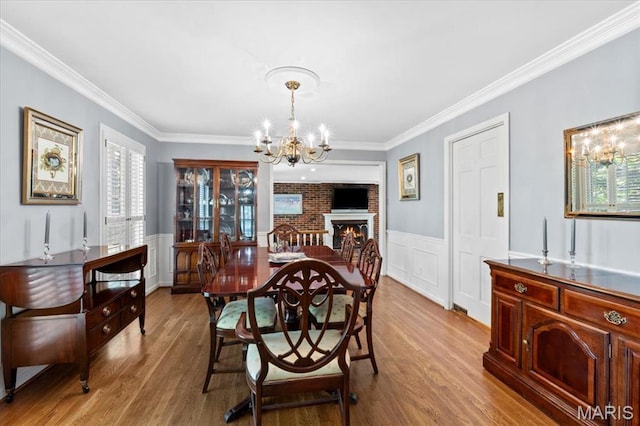 1843 Manor Hill Rd, Saint Louis, MO 63131 - dining room featuring a chandelier, wood finished floors, crown molding, wainscoting, and a brick fireplace