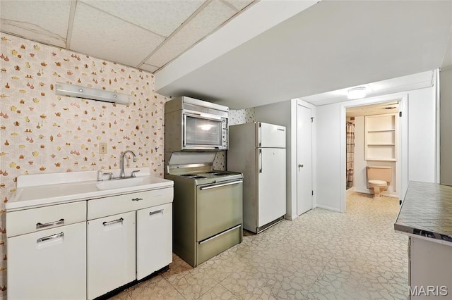 1467 Crystal Heights Rd, Crystal City, MO 63019 - kitchen with white appliances, wallpapered walls, a drop ceiling, light floors, and white cabinets