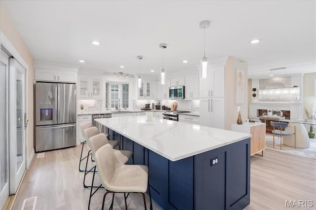 447 Maymont Dr, Ballwin, MO 63011 - kitchen featuring stainless steel appliances, white cabinets, light wood-style floors, glass insert cabinets, and decorative backsplash