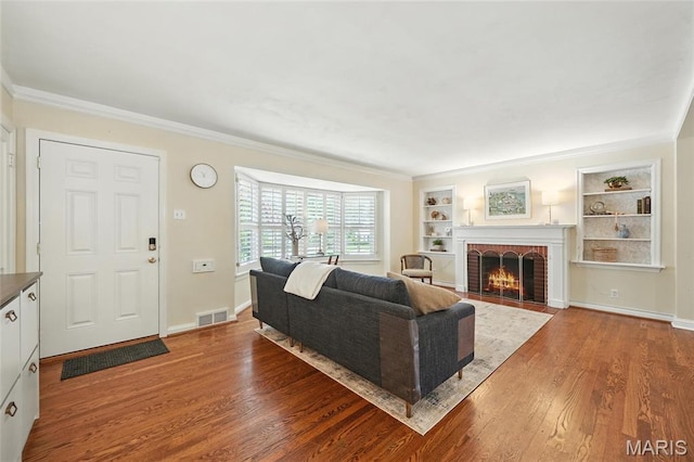 906 N Taylor Ave, Saint Louis, MO 63122 - living room with wood finished floors, a fireplace, built in shelves, and crown molding