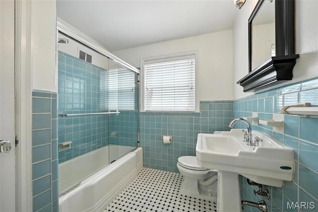 906 N Taylor Ave, Saint Louis, MO 63122 - bathroom with tile walls, combined bath / shower with glass door, and a wainscoted wall