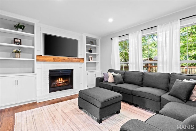 1026 Timber Creek Ln, Ofallon, IL 62269 - living area featuring healthy amount of natural light, a fireplace, wood finished floors, and built in shelves