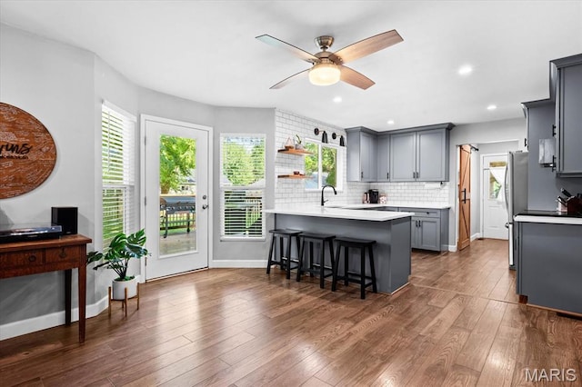 1026 Timber Creek Ln, Ofallon, IL 62269 - kitchen featuring gray cabinets, a peninsula, a breakfast bar, ceiling fan, and open shelves