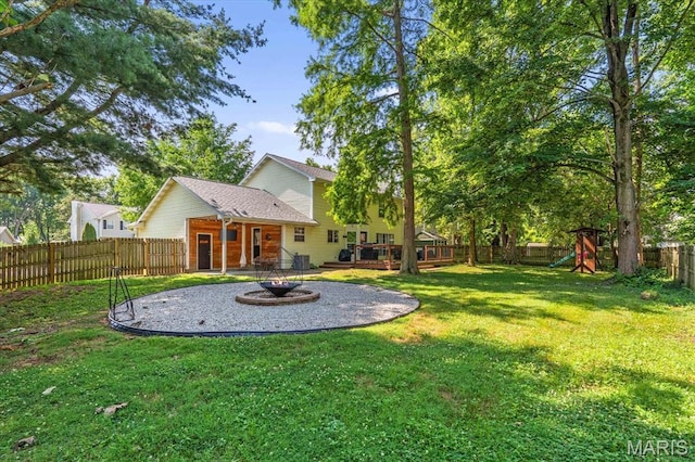 1026 Timber Creek Ln, Ofallon, IL 62269 - fenced backyard featuring a fire pit, a playground, a wooden deck, and a patio area