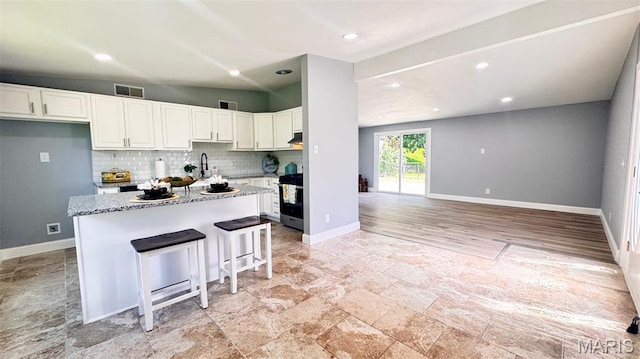 6822 Friarwood Dr, Saint Louis, MO 63134 - kitchen featuring decorative backsplash, white cabinetry, stainless steel range with electric stovetop, light stone countertops, and recessed lighting