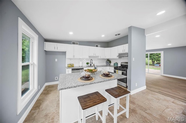 6822 Friarwood Dr, Saint Louis, MO 63134 - kitchen featuring stainless steel appliances, under cabinet range hood, white cabinetry, a center island, and recessed lighting