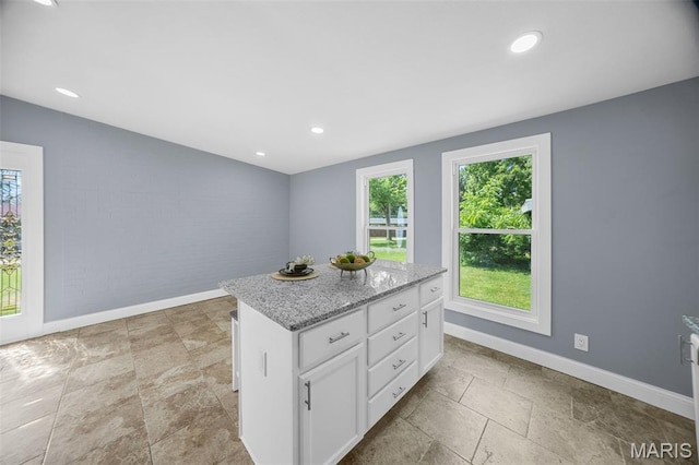 6822 Friarwood Dr, Saint Louis, MO 63134 - kitchen featuring white cabinetry, stone tile flooring, a kitchen island, recessed lighting, and light stone countertops